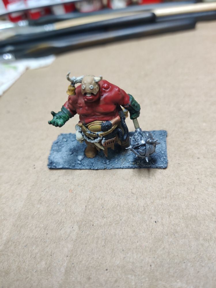 A miniature of a demon. in their left hand is a morning star filled with bones.