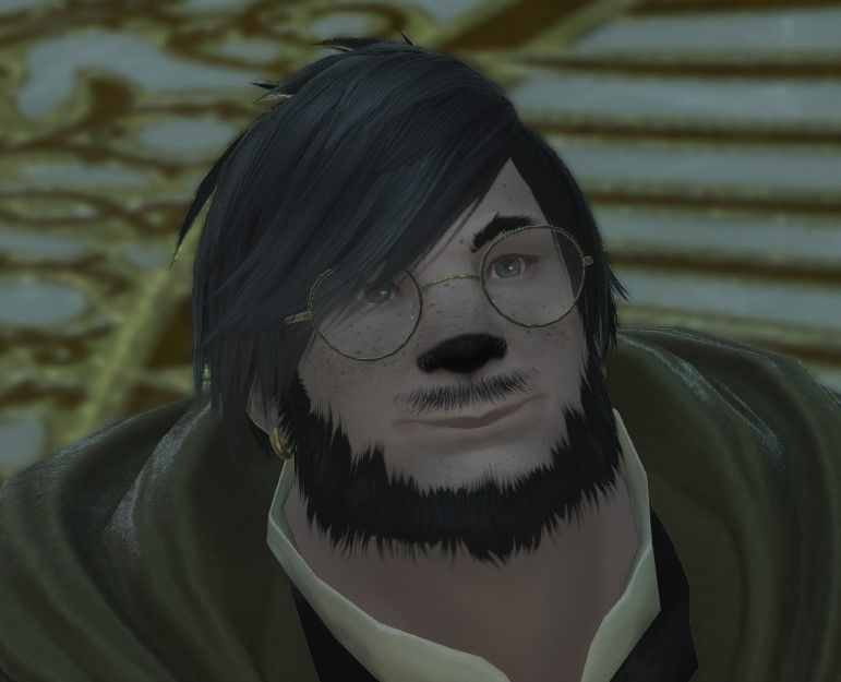 A large man with dark hair and large glasses aggressively presses his lips together into a goofy smile. 