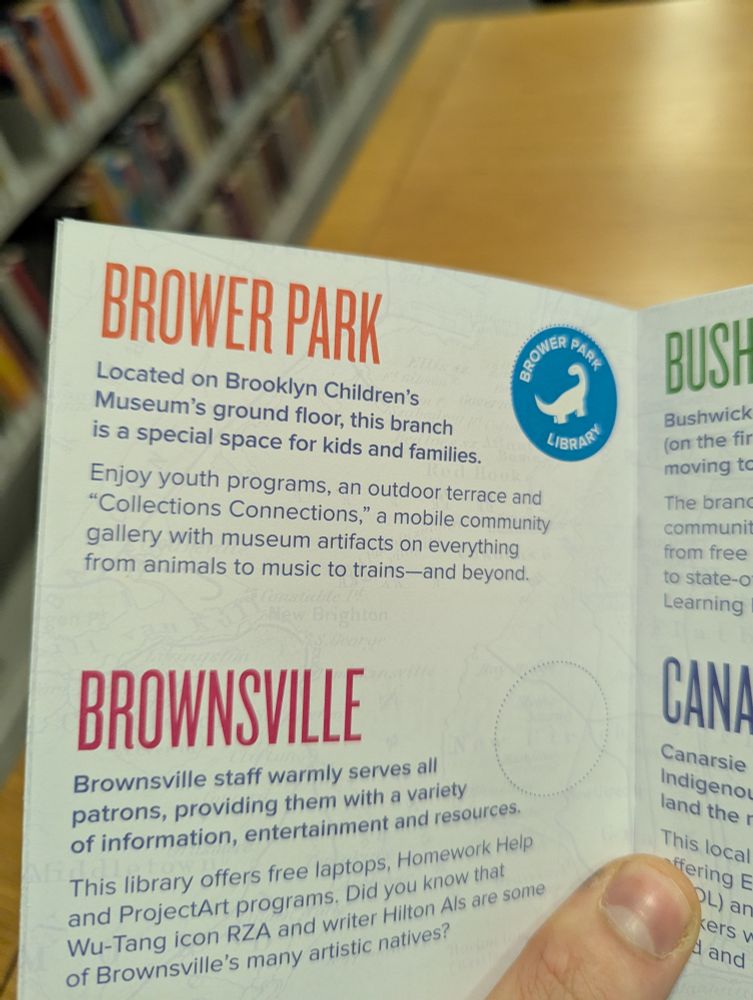 A photo of a booklet listing the Brooklyn library branches, with focus on the Brower Park branch. The text reads, "Brower Park. Located on Brooklyn Children's Museum's ground floor, this branch is a special space for kids and families. Enjoy youth programs, an outdoor terrace and 'Collections Connections,' a mobile community gallery with museum artifacts on everything from animals to music to trains—and beyond." A blue sticker with the outline of a dinosaur and the text, "Brower Park LIbrary" is attached next to the text.