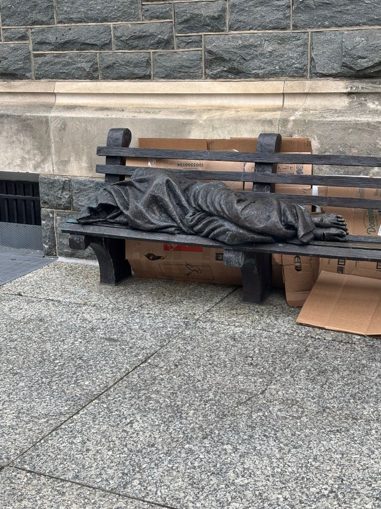 Statue of person sleeping on bench with stigmata 