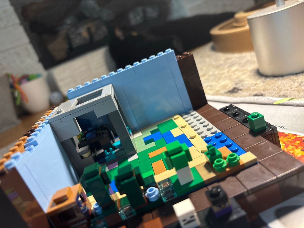 partially constructed Minecraft crafting table LEGO set with a black cat in the background 