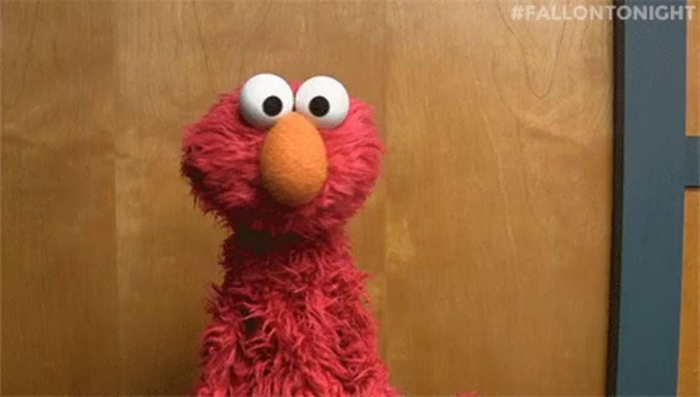 elmo from sesame street standing in front of a wooden wall