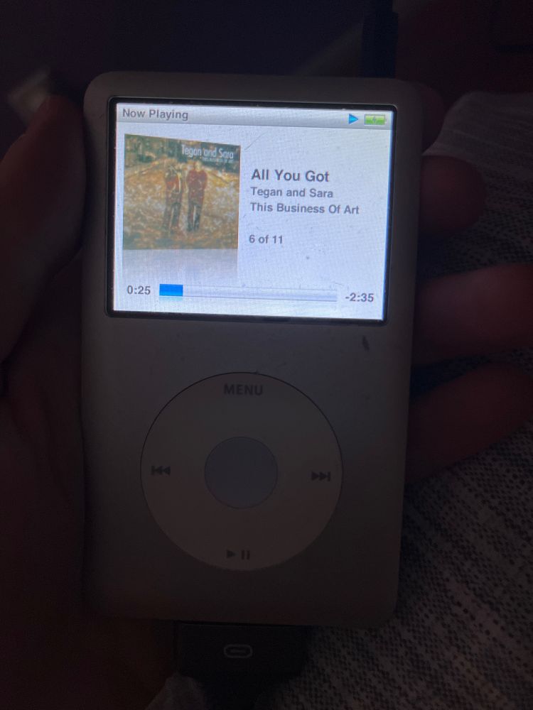 My hand holds a gray iPod classic last used in maybe.. 2015? On the left of its screen is the album art for Tegan and Sara’s This Business of Art. All You Got  is played at 0:25/-2:35 and is track 6 of 11 in the album. 

Unpictured is my overwhelming joy 