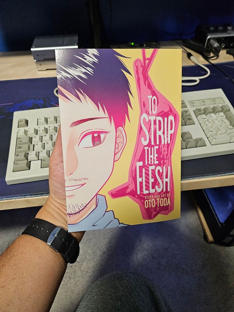 A picture of me holding the manga collection "To Strip The Flesh" in my hand