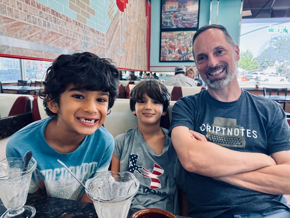 An uncle sits in a diner with his nephews, one of whom is missing his two front teeth