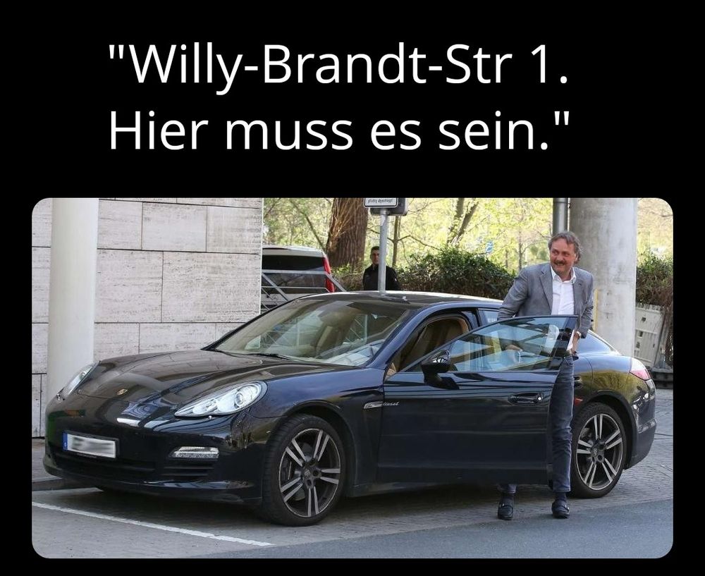 Peter Neururer steigt in einem grauen Anzug aus seinem schwarzen Porsche. 
