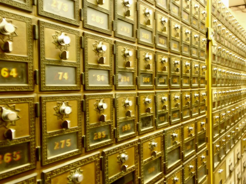 A wall of gold-colored boxes with knob-style locks.  Each key-box has a number, the series of which fades off into the distance.