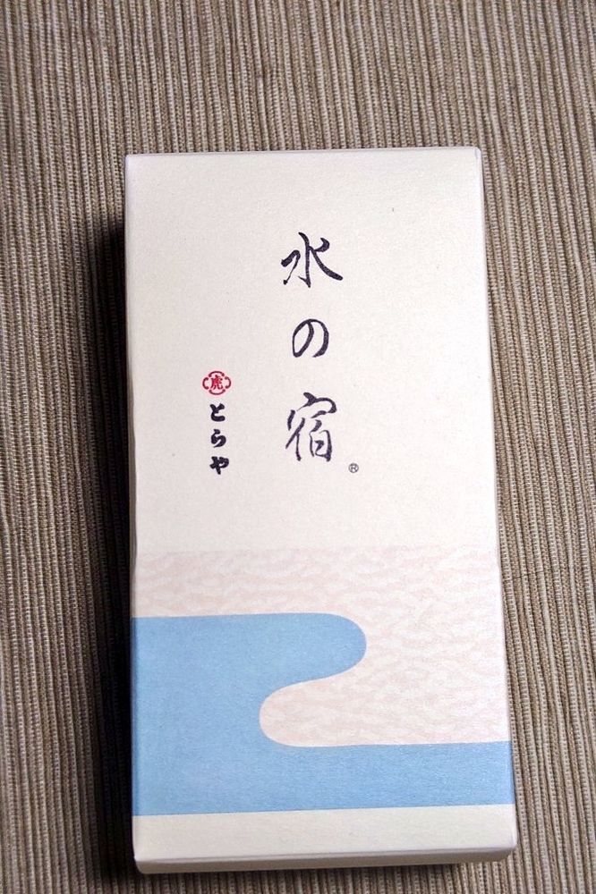 とらやの季節の羊羹・水の宿（みずのやどり）のパッケージ。
白い縦型の紙箱の下部に、二種の流水文を組み合わせて羊羹の意匠を描いている。