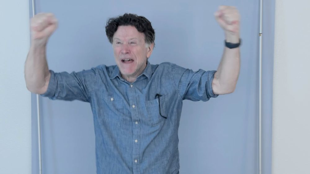 Photo of a man with a very excited face and outstretched arms.