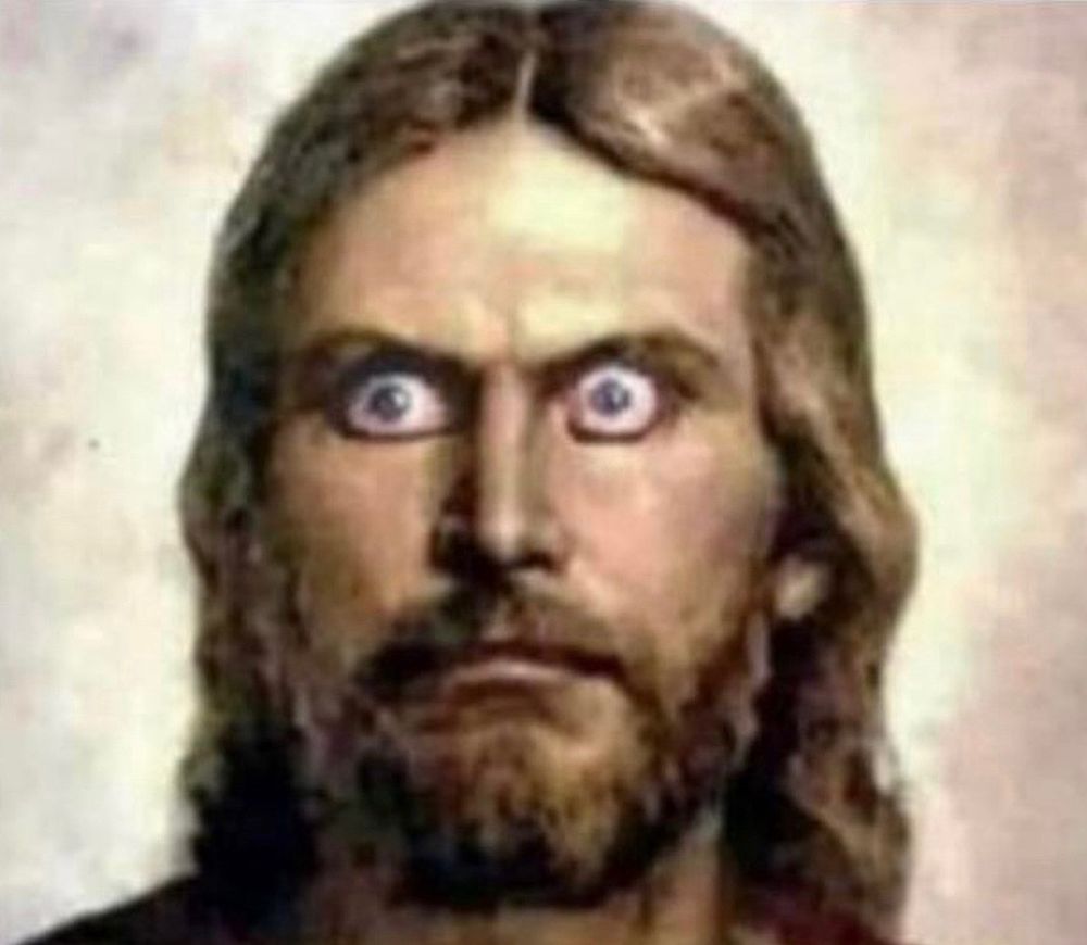 A man with a beard and long hair staring with wide bulging eyes 