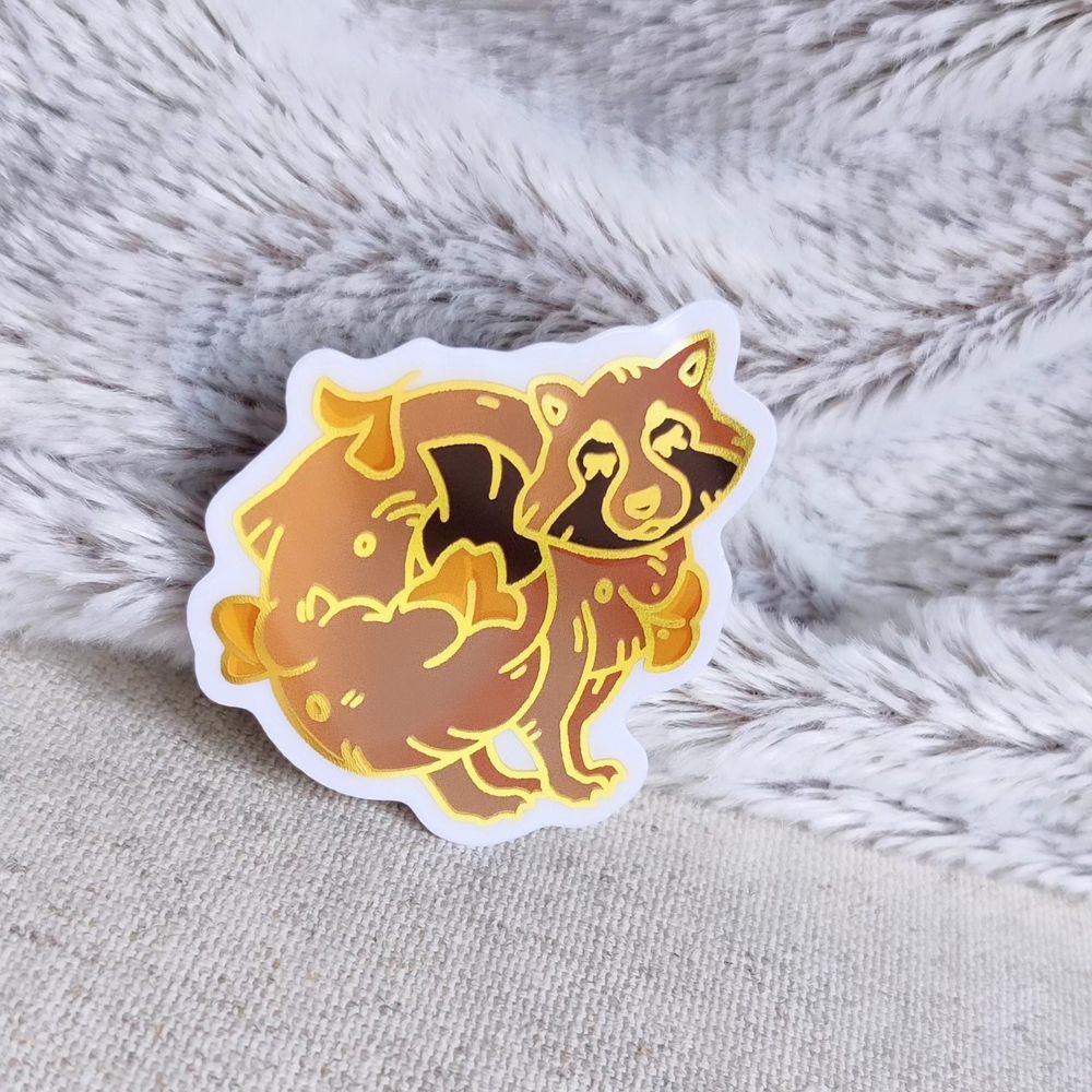 Un petit stickers aux contours effet doré, représentant un Tanuki jouant dans les feuilles aux couleurs d'automne. D'un coup de queue, il fait voler les feuilles autour de lui.