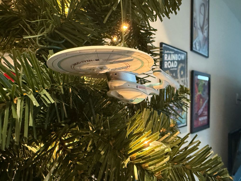 The Hallmark Christmas ornament version of the USS Enterprise NCC-1701-B, hanging on a Christmas tree
