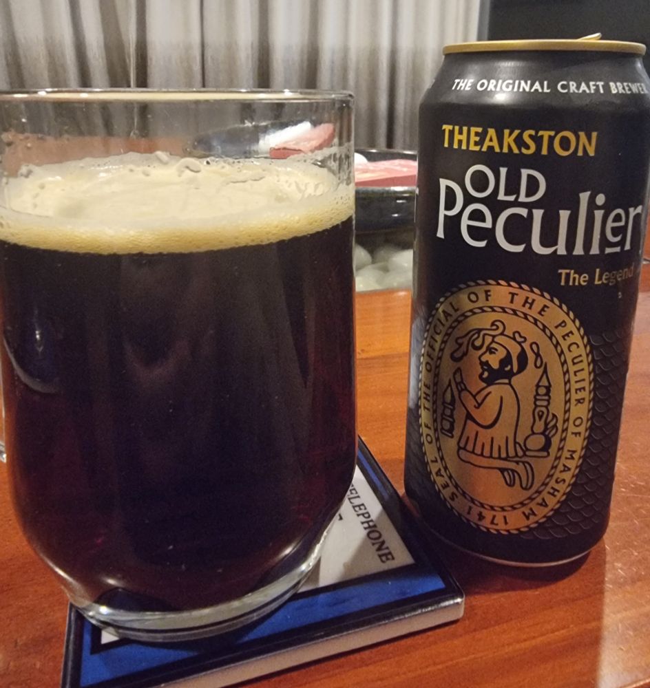 Glass of dark brown beer next to the can. 
