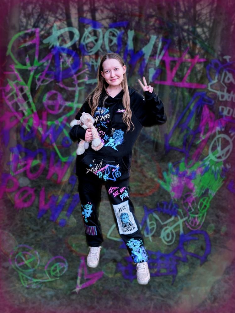 Nonika wearing the Arcane outfit from Hot Topic, doing a peace sign and holding Junkcat. The background is edited to be covered in Jinx's graffiti.