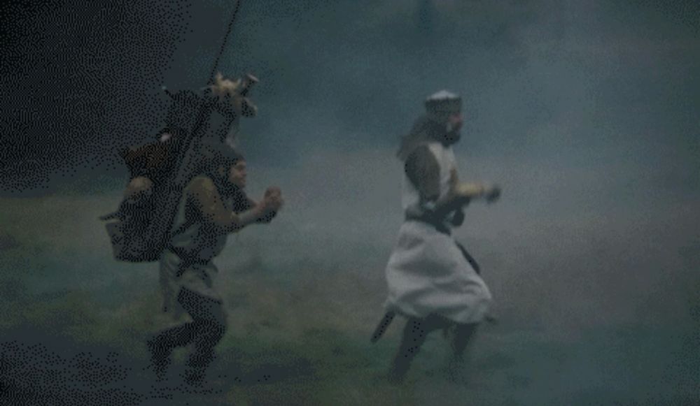 A misty scene from the Monty Python film ‘The Holy Grail’. King Arthur leads the way as he and Patsy are pantomiming riding horses. Patsy adds galloping horses sound effects with two halves of coconut shells