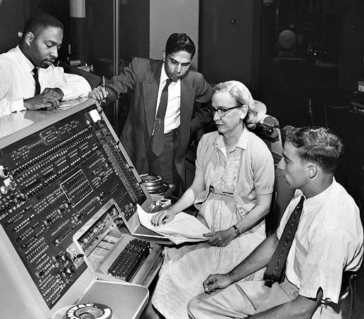 Grace Murray Hopper at the UNIVAC keyboard, c. 1960. Grace Brewster Murray: American mathematician and rear admiral in the U.S. Navy who was a pioneer in developing computer technology, helping to devise UNIVAC I. the first commercial electronic computer, and naval applications for COBOL (common-business-oriented language).

In this black‑and‑white image, Admiral Grace Hopper sits at the UNIVAC I operator console, surrounded by three colleagues. She is positioned center‑right, with her hands likely resting on the machine's keyboard or control panel. Two men lean in from either side—one seated beside her and another standing behind—suggesting a collaborative atmosphere around the sizable, angled console.

https://upload.wikimedia.org/wikipedia/commons/3/37/Grace_Hopper_and_UNIVAC.jpg