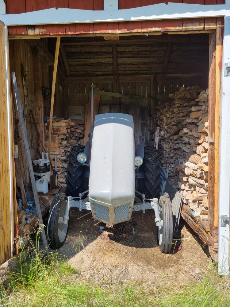 Picture of a gray 1953 Ferguson TEA20B standing in a small tractor garage on the countryside. Hood open for access to the cooling hoses that need replacement.