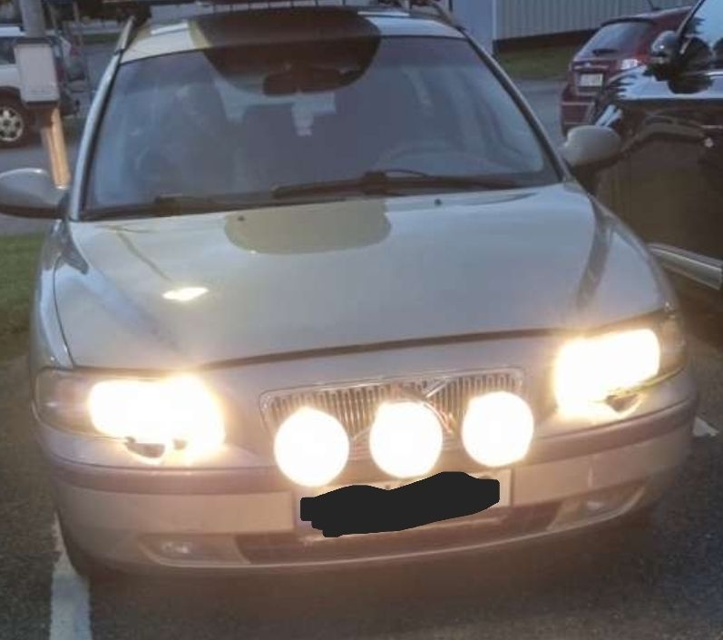 Picture of a Volvo V70's front. Mounted three not so cool Hella 500 halogen lights above the registration plate, in front of the grille. Will be good when the dark time of the year comes here up in the north. 