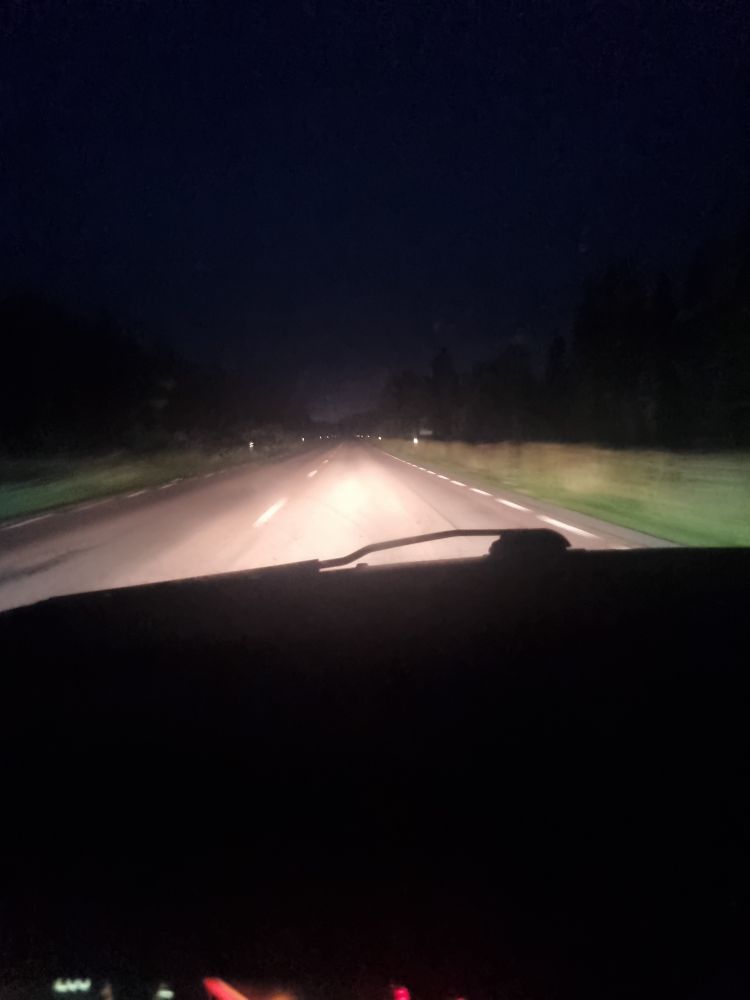 Picture from my car. It's dark outside, you can hardly see the forest surrounding the road. The headlighs illuminate the road and part of the sides. Had to go.