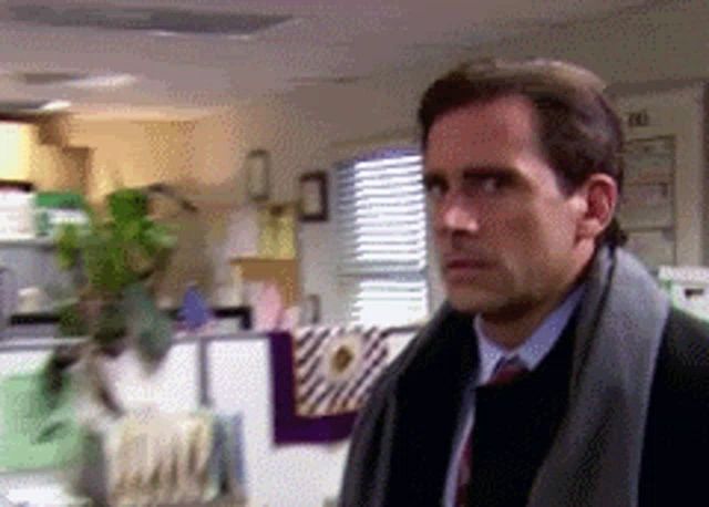 a man in a suit and tie is standing in a room with a calendar on the wall