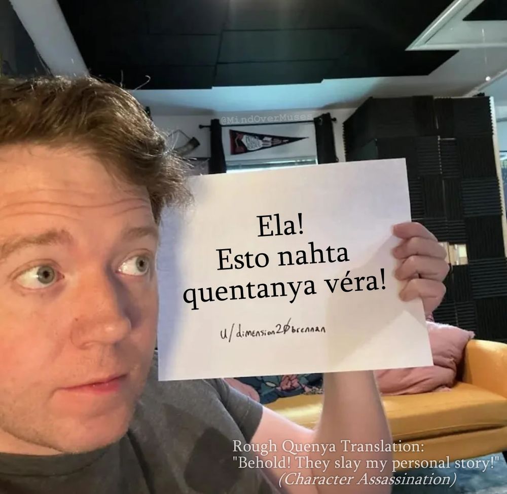 Brennan Lee Mulligan holding up a piece of paper from a Reddit AMA that's been edited to remove the original information he wrote on it. Replaced is a, from the creator, "most-likely poorly conjugated" attempt to translate "Character Assassination" into J.R.R. Tolkien's Quenya language. It reads: "Ela! Esto nahta quentanya vera!" and has a rough translation listed as "Behold! They slay my personal story!"
