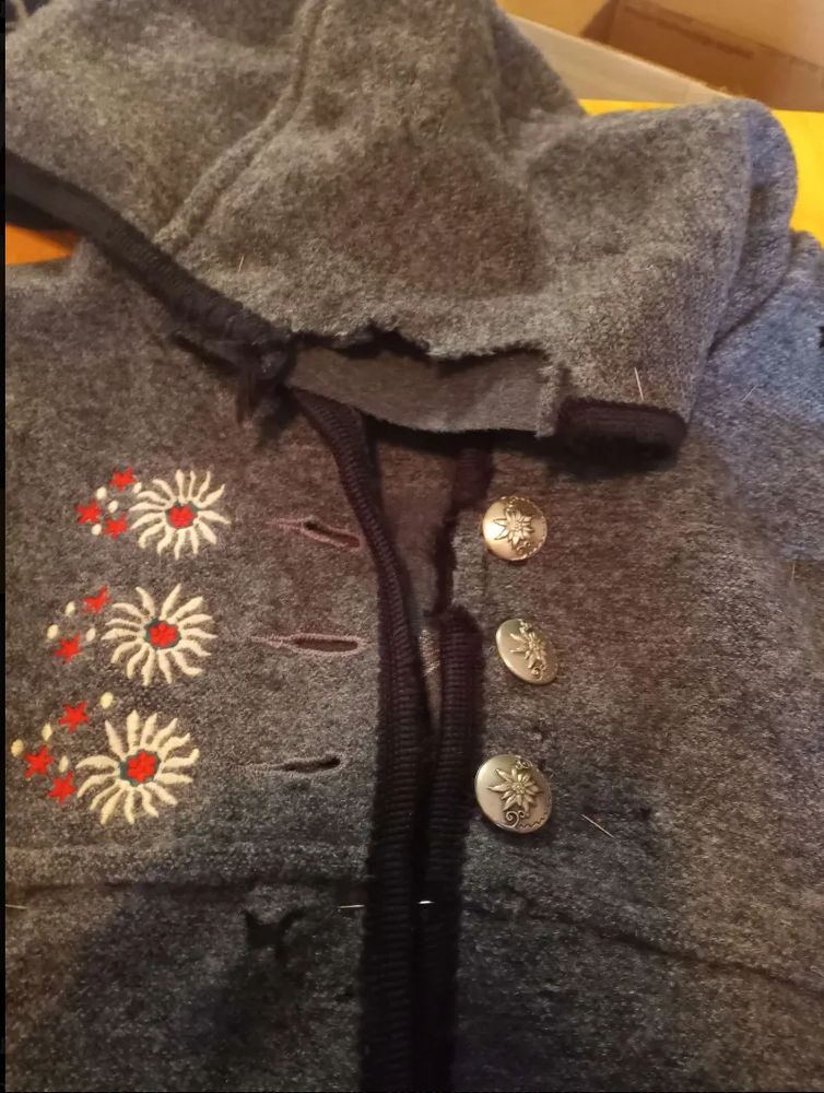 a very moth eaten upper section of the coat, with a lot of damage at the hood and a cute little embroidery near the 3 button holes. there are nice silver buttons, but the moths have destroyed the binding near them