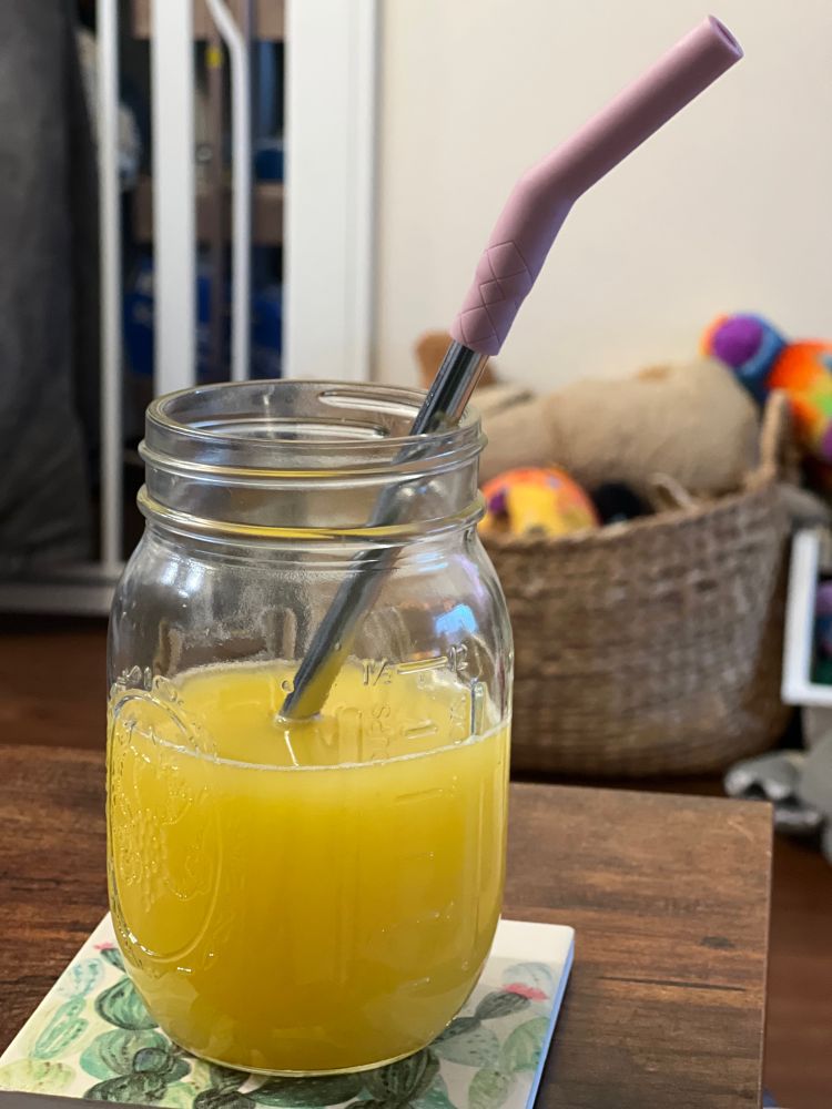 Mimosas in a mason jar with a reusable straw. Dog toys in the background. 