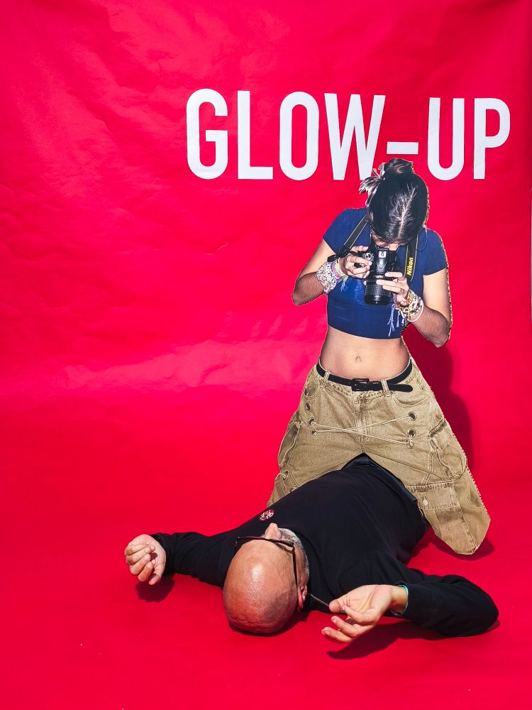 Fotografía inspirada na película Blow up, de Michelangelo Antonioni.
Aquí o texto está cambiado por "Glow up"
Un home deitado no chan (eu) está a ser fotografado por unha muller sentada a cabalo del. Para a foto empregouse un afiche de cartón, e non unha muller de verdade.