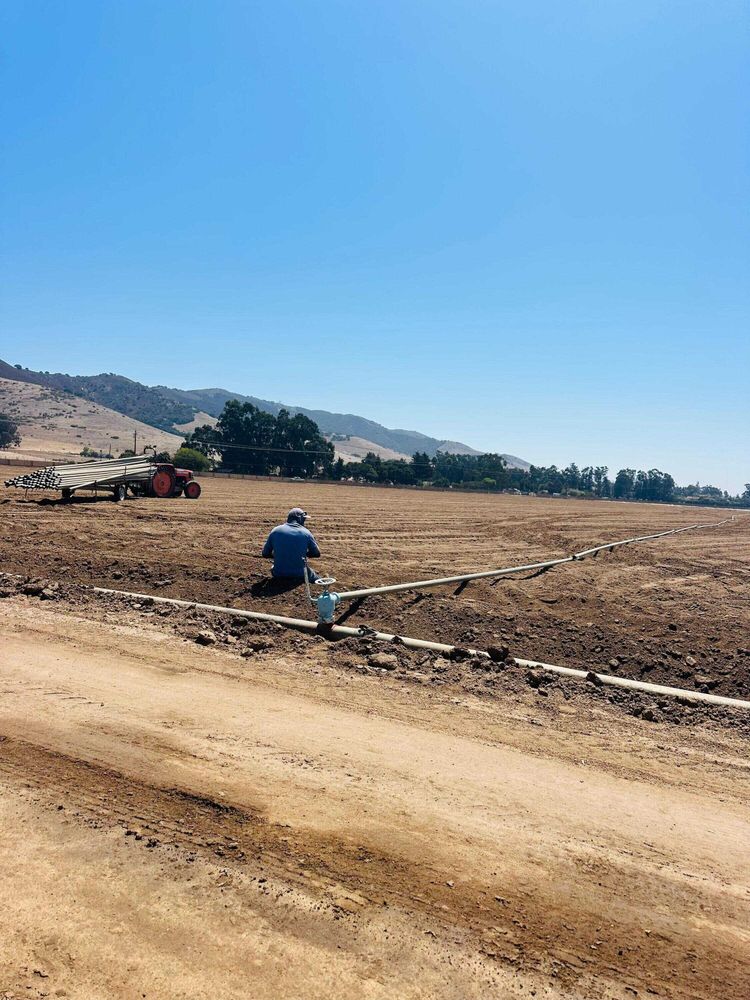 An irrigator setting up pipes in an empty field