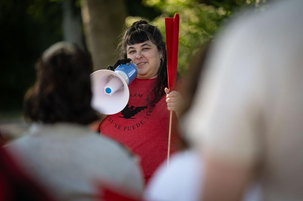 UFW organizer speaking into a megaphone at a rally demanding the release of farm workers detained by ICE earlier this month