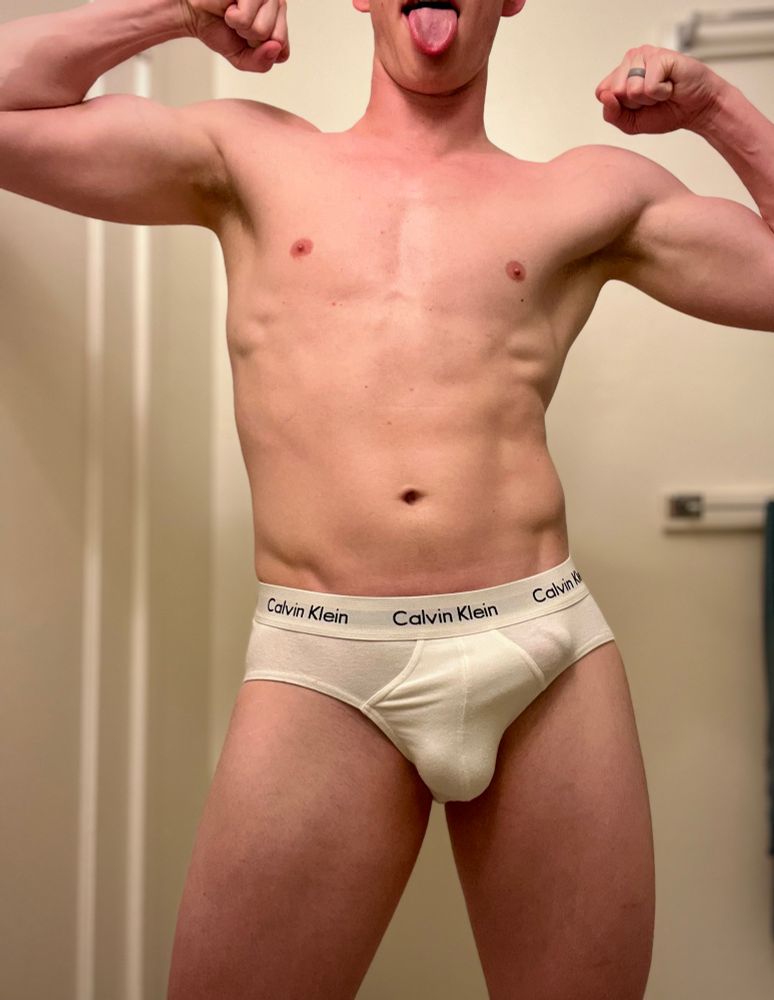 Flexing naked in a pair of classic white Calvin Klein briefs, with a visible bulge outline