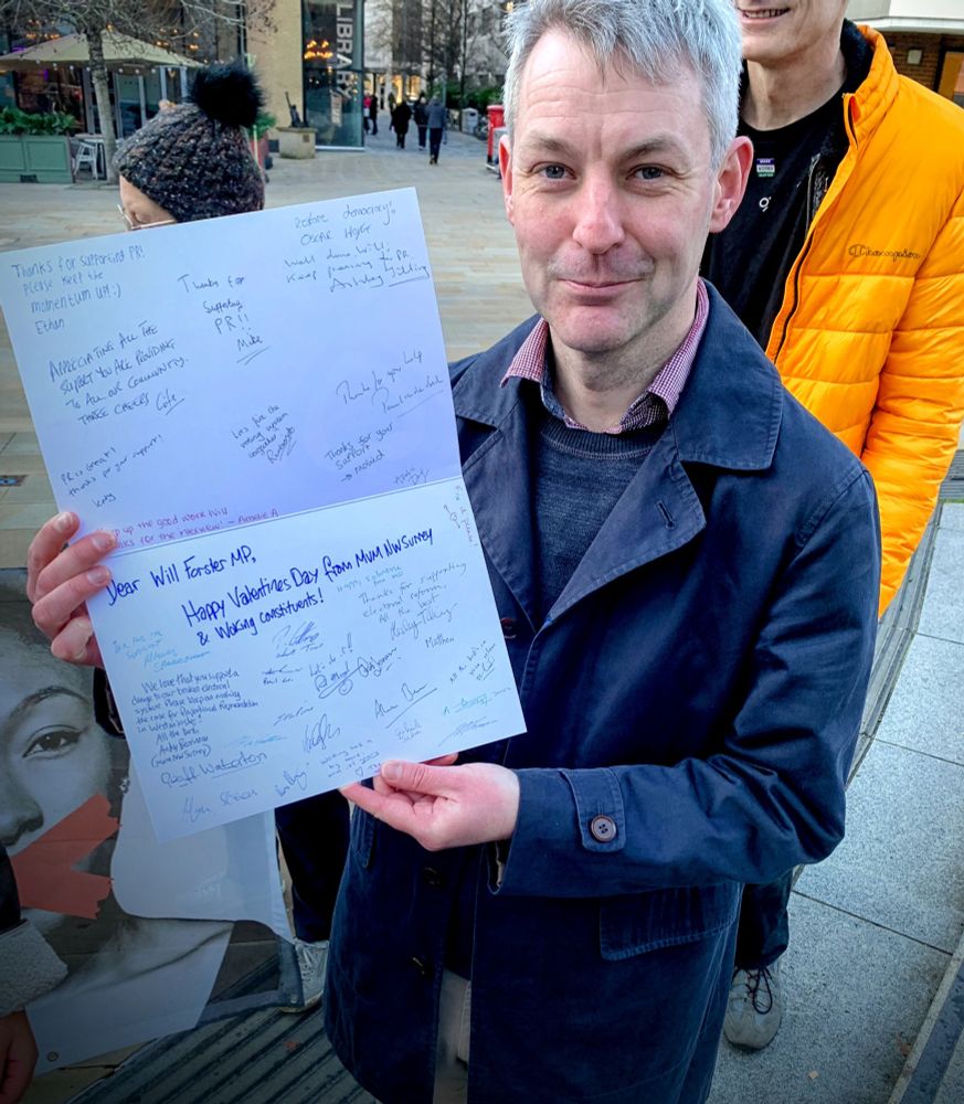 Will Forster MP holding a card signed by his constituents 