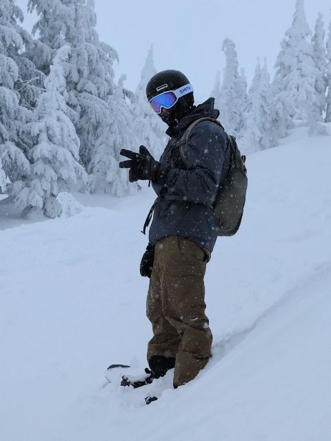 GIF of snowboarder nodding his head and giving the peace on a snowy mountain slope