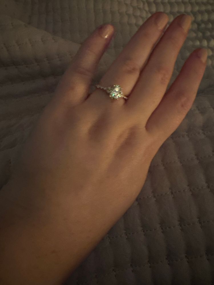 A hand with a moissainite engagement ring yellow gold band 