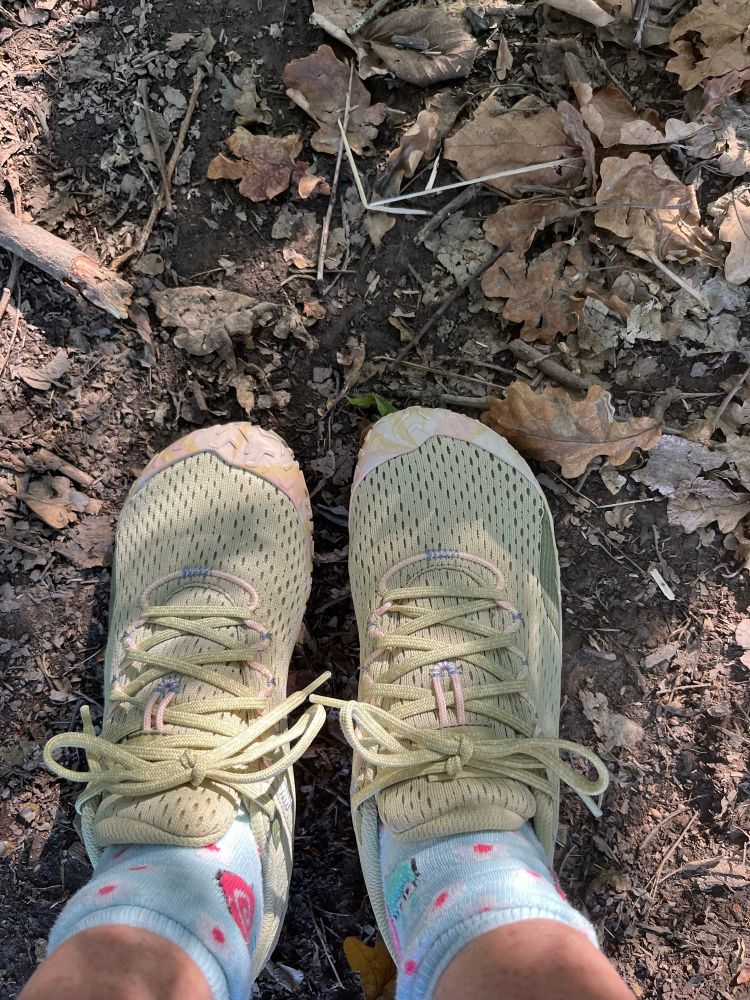 feet in a pair of green walking shoes on a woodland path