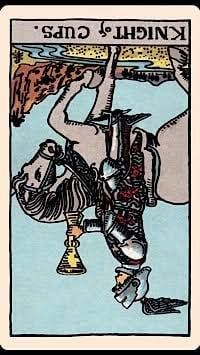 Knight of cups tarot card in the reversed, or upside down, position. The card shows a single knight on a grey horse. He is holding a golden goblet in front of a plain, blue background. 