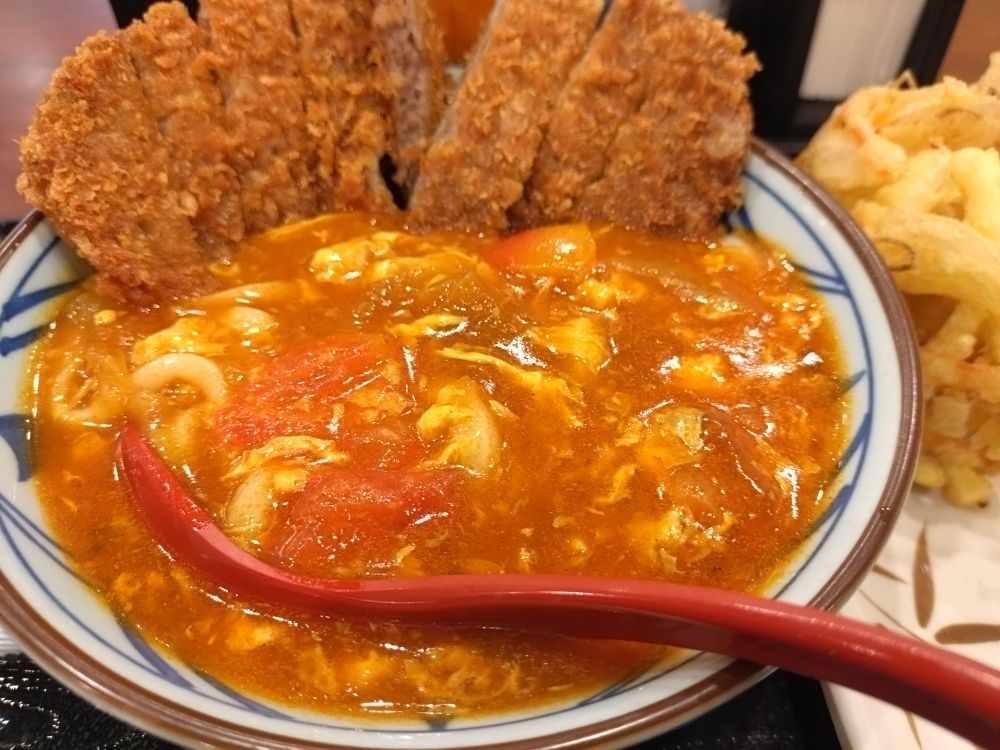 丸亀製麺の牛カツトマたまカレーうどん（並）の写真　野菜かき揚げ添え