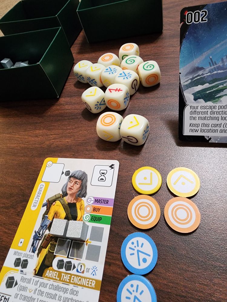 Starting characters card and tokens for a solo play of Vantage boardgame by Stonemeier Games.  Also shown are skill dice with various colored symbols representing skills needed in game.  A side shot of an opening location to be explored by the character is shown partial off-camera.  Various tokens representing skills to be used (yellow, blue, and orange here) are shown next to the yellow Engineer character card.