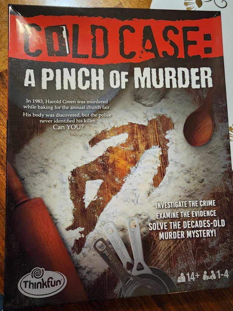 Cover box to the murder mystery game Cold Case: A Pinch of Murder by ThinkFun Games.  Cover shows the title of the game in bold red banner at the top.  The outline of a human body is made in a large pile of flour with several baking utensils surrounding it, including a rolling pin, several  measuring cups, and a wooden spoon.