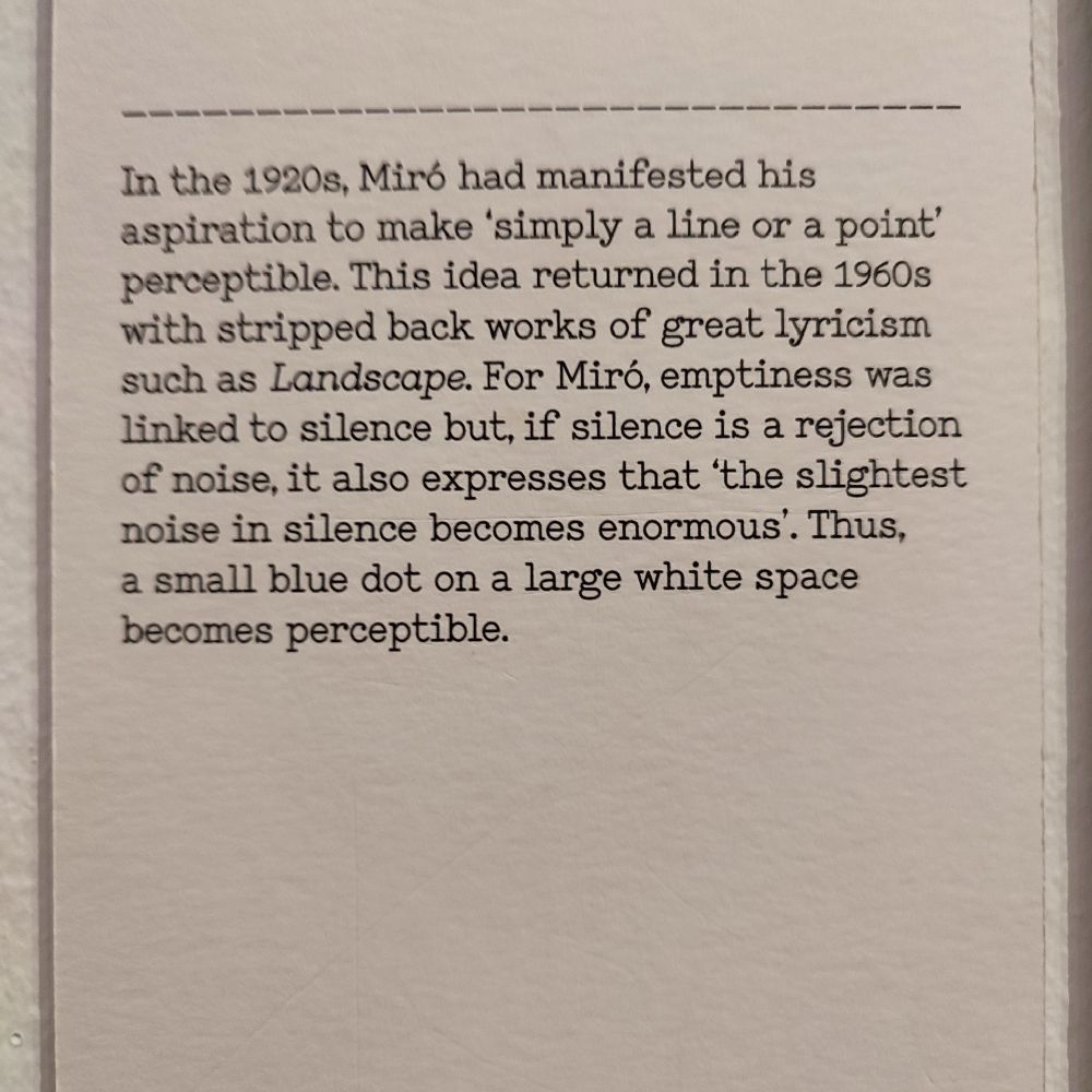 A museum wall text explains Joan Miró’s aspiration from the 1920s to make “simply a line or a point” perceptible, revisited in the 1960s in minimalist works like Landscape. It discusses how, for Miró, emptiness was linked to silence, and how even the smallest mark becomes significant within a vast empty space, likening it to a tiny blue dot on a large white surface.