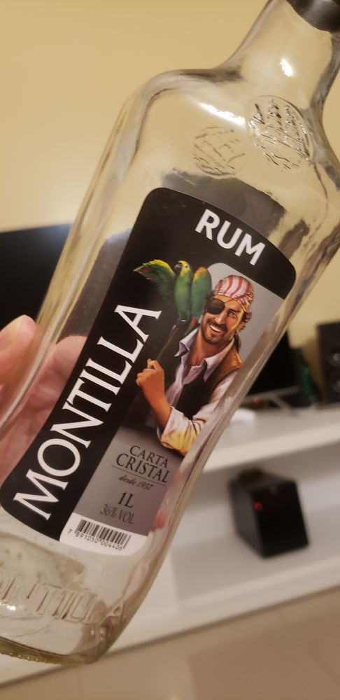Minha mão segurando uma garrafa vazia de Rum Montilla