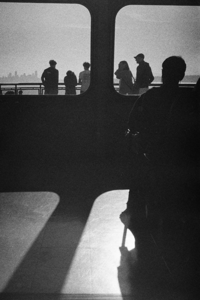 Black and white photo of people through the windows of a ferry in the Puget Sound