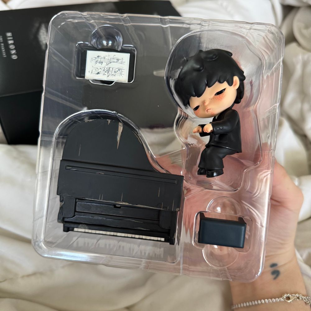 hirono pianist figurine. he looks like yoongi ahhhhh!! he’s wearing a fancy suit and in a position that looks like he’s playing piano when sat on the piano bench. there’s also a piano bench, a worn piano and sheet music.