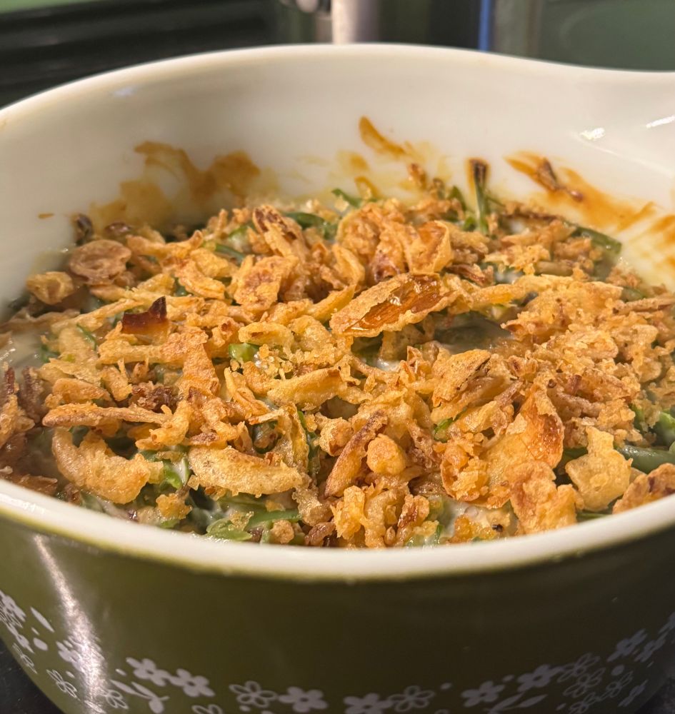 a green casserole dish with green beans and crispy onions on top (also cream of mushroom soup, milk, & spices!)