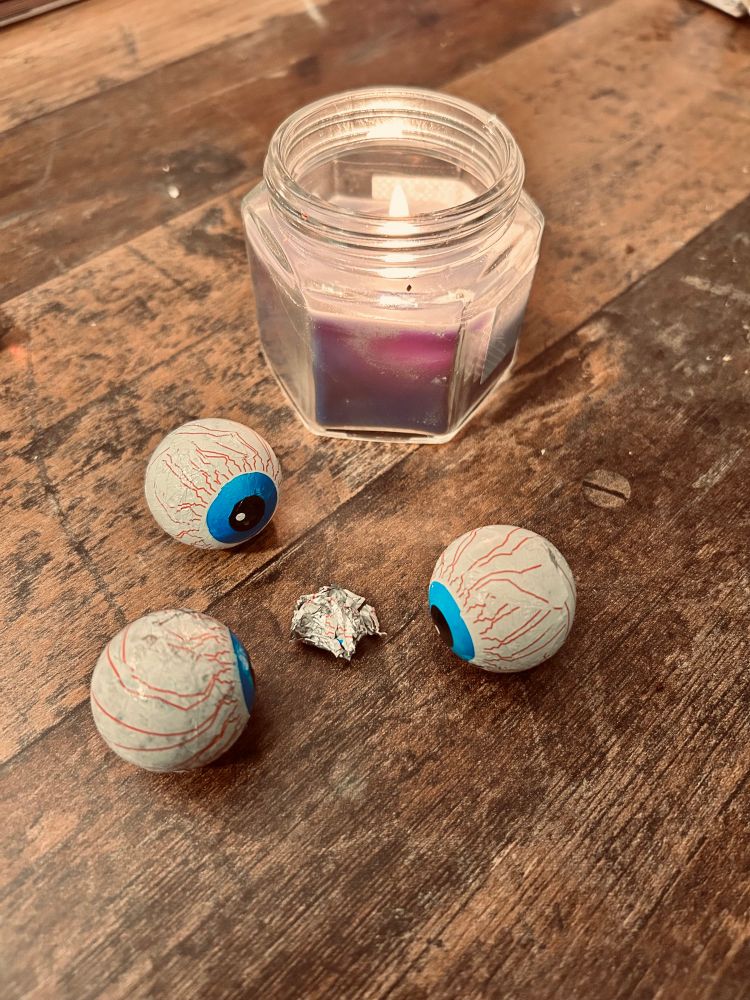 Drei Glubschaugen voe Kerze, dazwischen die zeusammengeknüllte Folie des Opfers. 