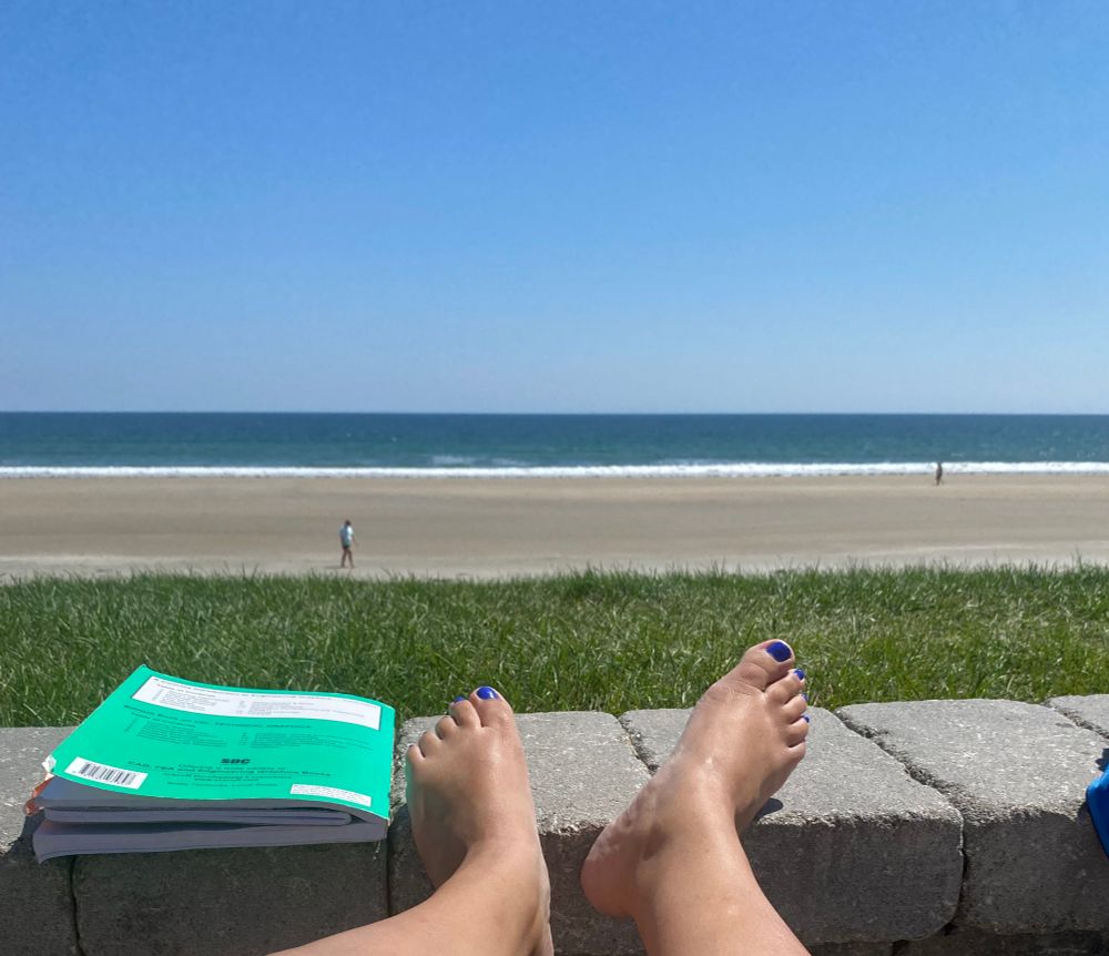 Feet resting on a stone wall with the beach as the landscape. 