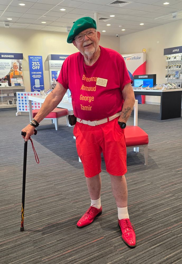 Stevie Joe is at US Cellular in Bartlesville, Oklahoma. He is wearing Red dancing shoes, in case a dance breaks out, bright Red solid color shorts from Hreski golf shorts, a Red t-shirt with the names "Breonna, Ahmed, George, Tamir," on the front, green French beret, and using a "House" cane with flames down the shaft. The back of the shirt, not visible in the photograph, reads "Black Lives Matter.”