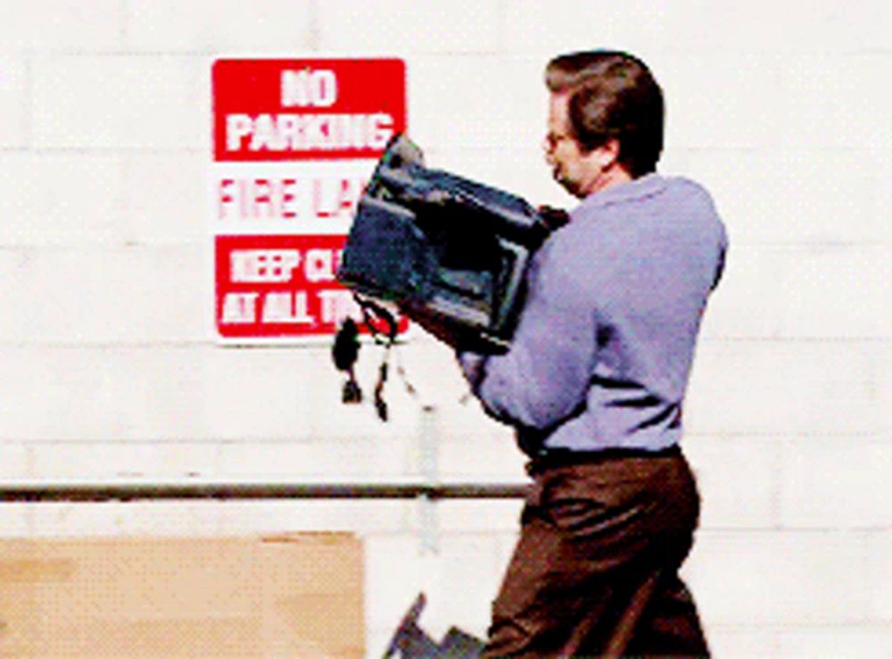 a man carrying a box in front of a sign that says no parking fire lane