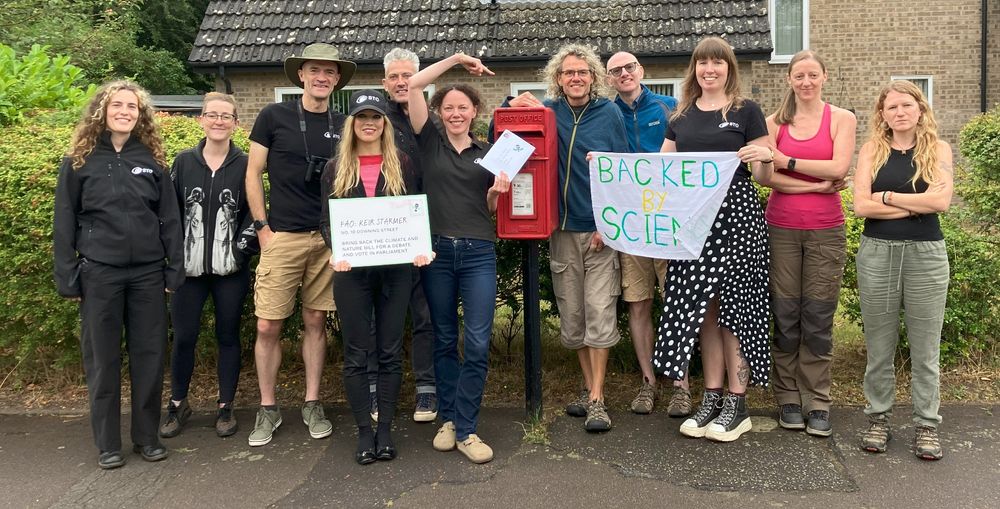 Group of BTO staff looking at the camera as they gather round the post box to post a letter to the Prime Minister.