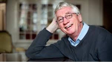 Frans De Waal als älterer Mann mit grauen kurzen Haaren lächelnd mit dem rechten Ellenbogen abgestützt sitzend und in die Kamera schauend 